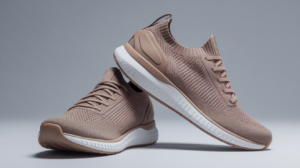 A pair of light brown Nexus Knit minimalist footwear by Xero Shoes with white soles. One shoe stands upright while the other leans against it, highlighting the side profile and details on a light grey background.